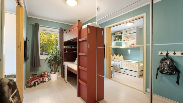 Stor skyvegarderobe og plassbygget køyeseng/høyseng med sofa under.
