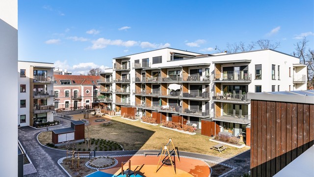 Utsyn over Skarmyrakvartalets parkmessige tun, med lekeapparater og stor tumleplass for de yngste beboerne.