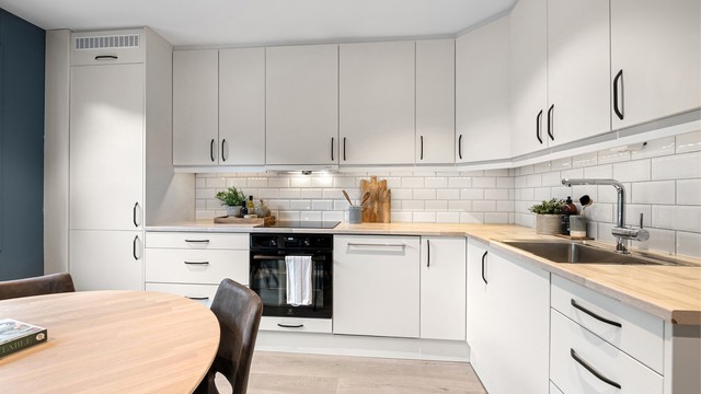 Kjøkkeninnredning fra 2008 med hvite glatte fronter og benkeplate med laminert overflate fra 2017