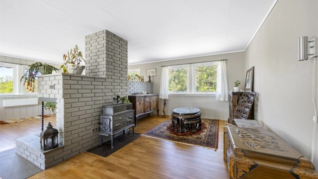 En sentral elementpipe fra byggeåret rommer to ildsteder som bidrar til oppvarming og atmosfære i stuen.