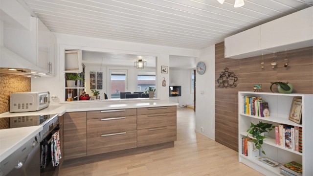 Kjøkkenet er pent og funksjonelt, og den delvis åpne, sosiale løsningen mot spisestuen skaper en naturlig og innbydende sone for både hverdagsmåltider og gjester.