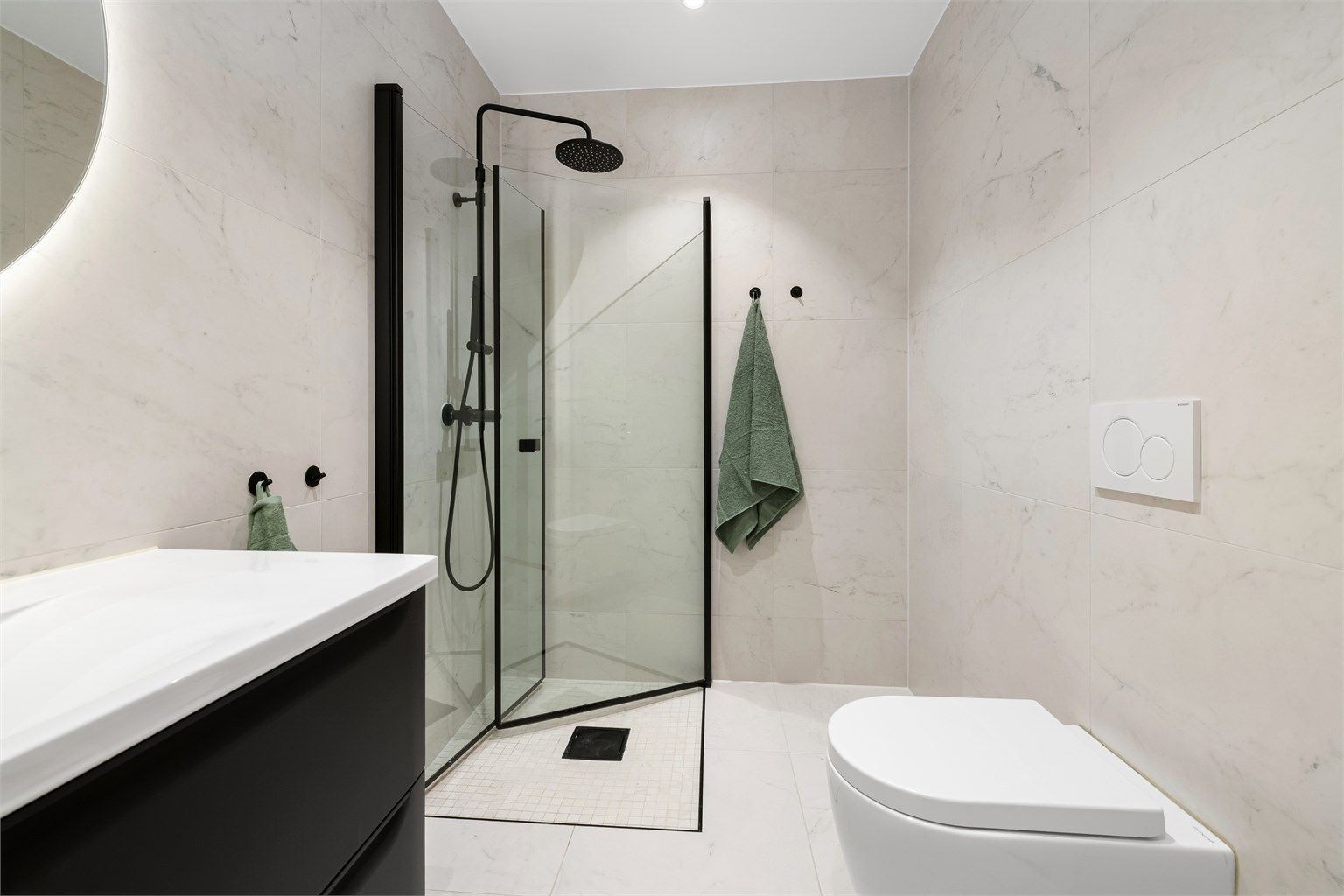 Badet har en romslig dusj med innfellbare glassdører og vegghengt toalett.