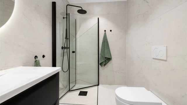 Badet har en romslig dusj med innfellbare glassdører og vegghengt toalett.