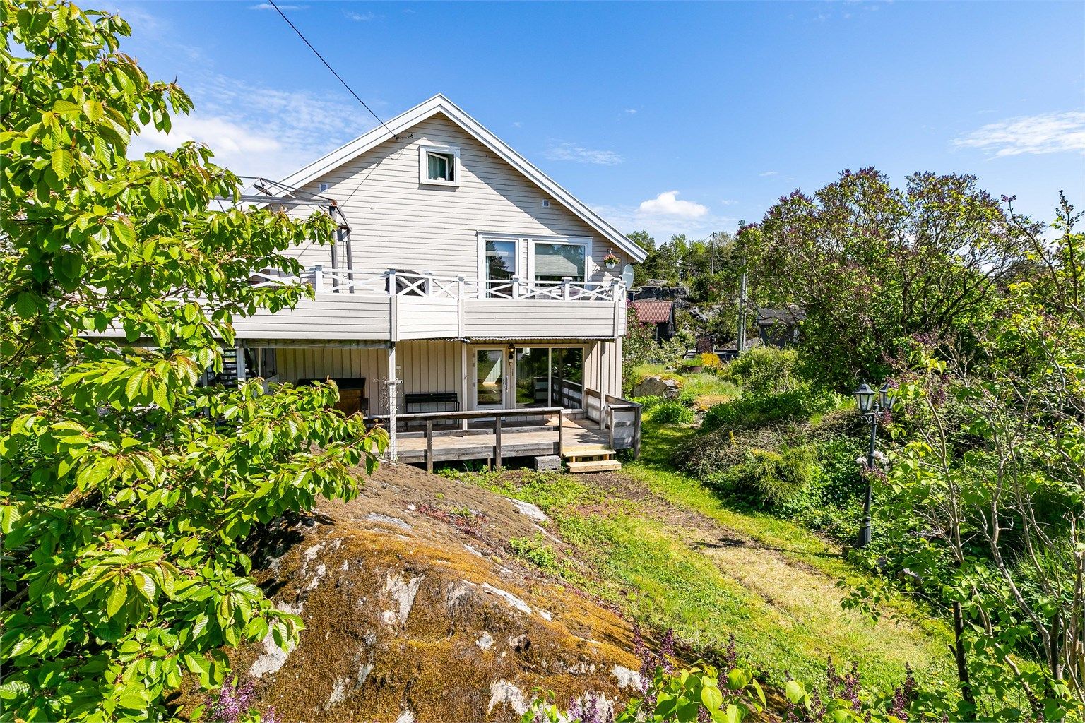 Leilighetene disponerer hver sin del av tomten. Leiligheten i første etasje tomten/hagen øst for fjellknausen. Fotograf; Børge Oppegård.