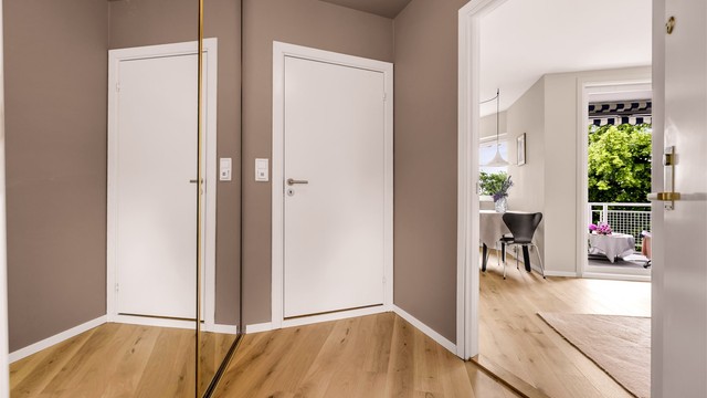 Lys og romslig entré med god plass for klesoppheng og oppbevaring av sko i skyvedørsgarderoben. På gulvet er det lagt parkett.