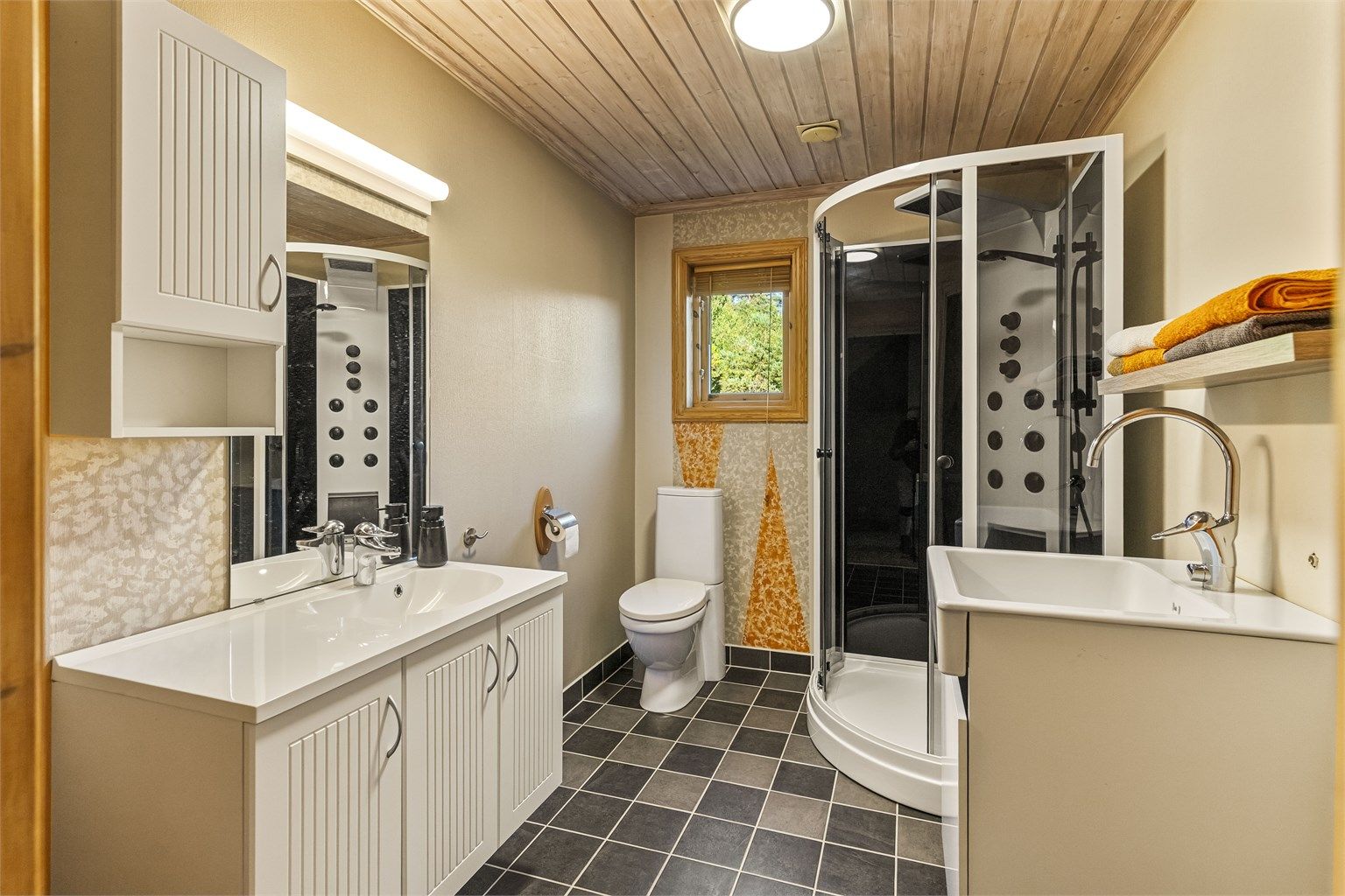 Badet i første etasje har flislagt gulv med varme, vegghengt servantskap og opplegg for vaskemaskin.