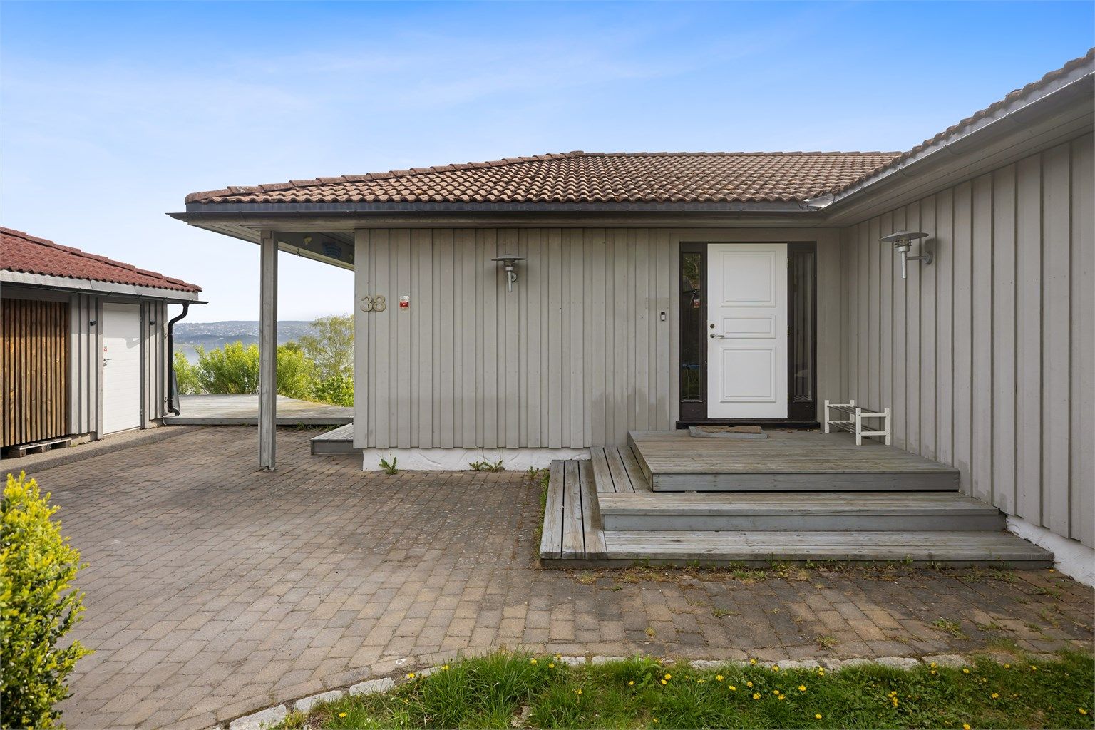 Gårdsplass med belegningssten samt vestvendt hage. 
