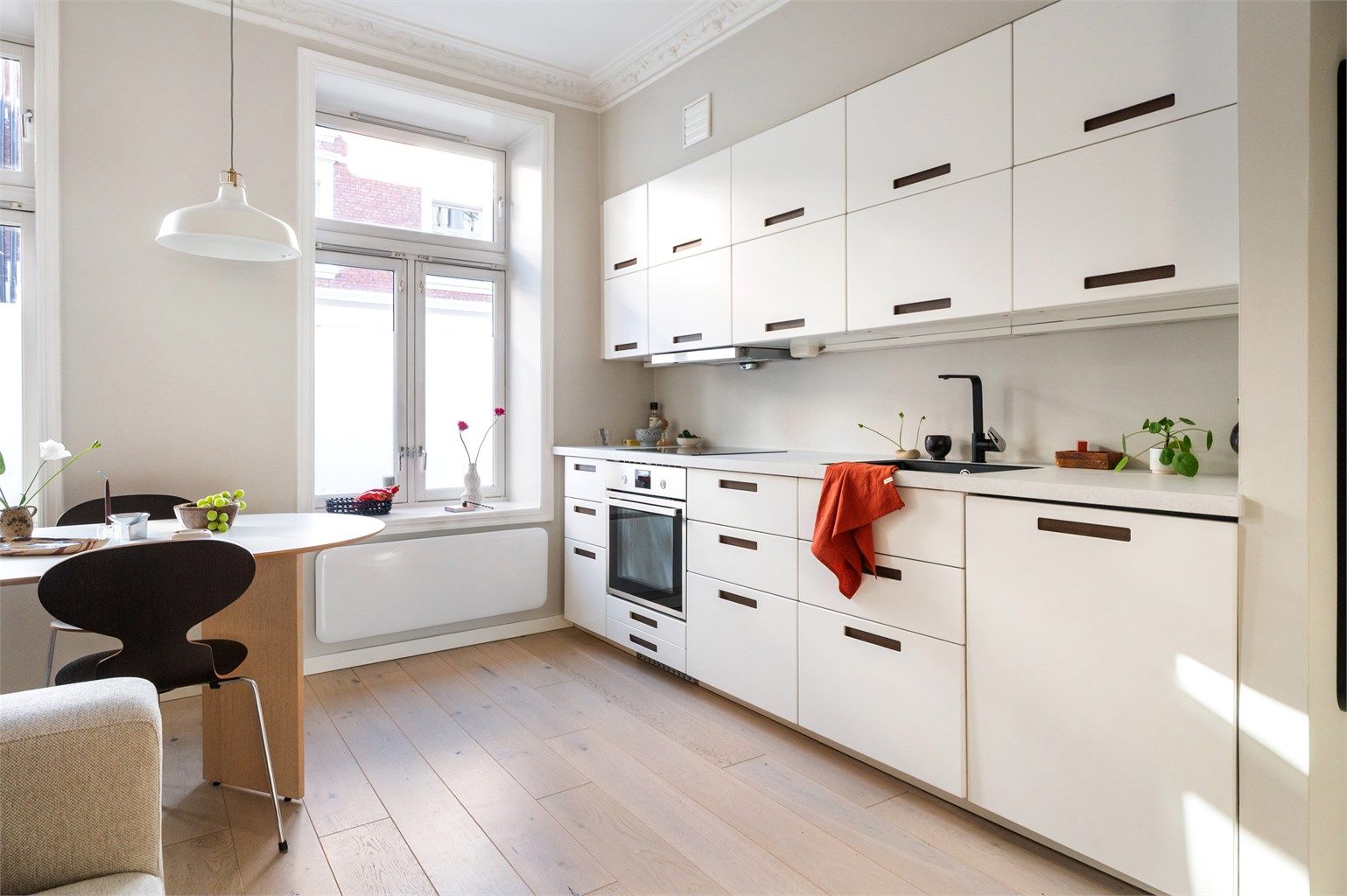 Kjøkkeninnredningen har glatte fronter og integrerte hvitevarer som induksjonstopp, stekeovn og oppvaskmaskin.