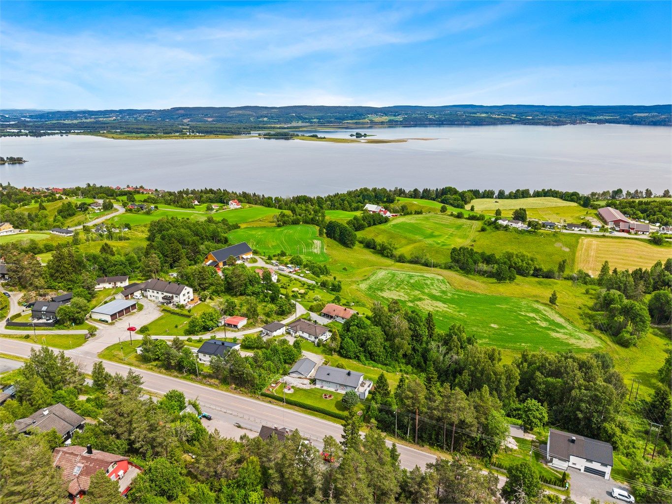 Eiendommens landlige beliggenhet med jorder, skog og utsikt mot Øyeren i bakgrunnen.