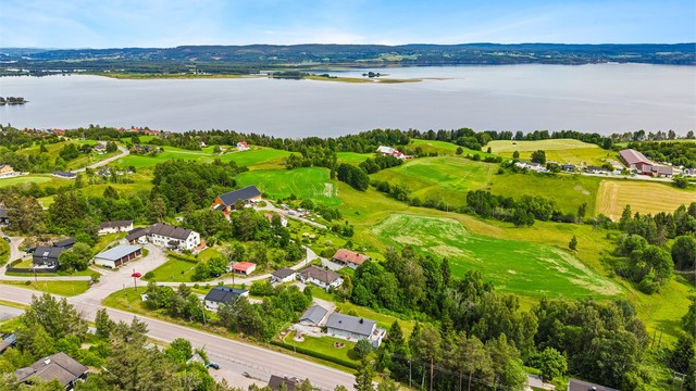 Eiendommens landlige beliggenhet med jorder, skog og utsikt mot Øyeren i bakgrunnen.