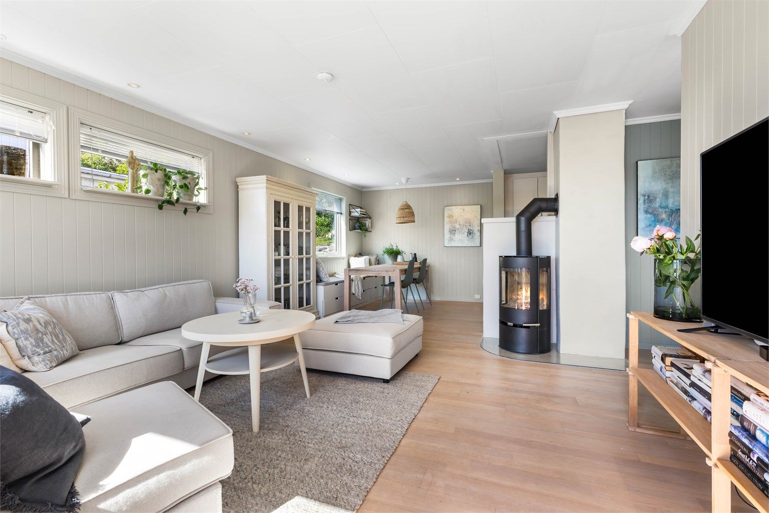 Stuen har en effektiv peisovn og plass til både sofagruppe og spisebord.
Foto: Sørvær Media