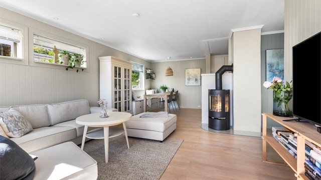 Stuen har en effektiv peisovn og plass til både sofagruppe og spisebord.
Foto: Sørvær Media