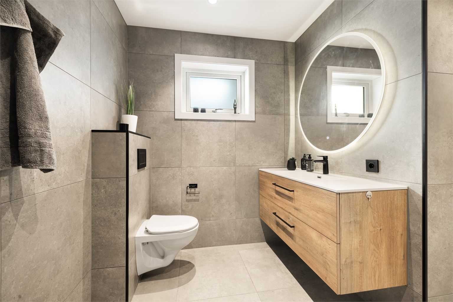 Meget delikat bad med store grå fliser på gulv og vegger. Varmekabler i gulv.