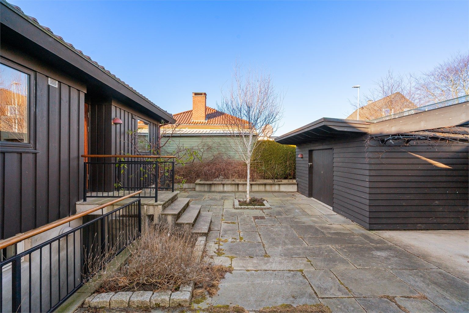 Stort gårdsrom med biinngang, utebod, søppelskur, samt carport.