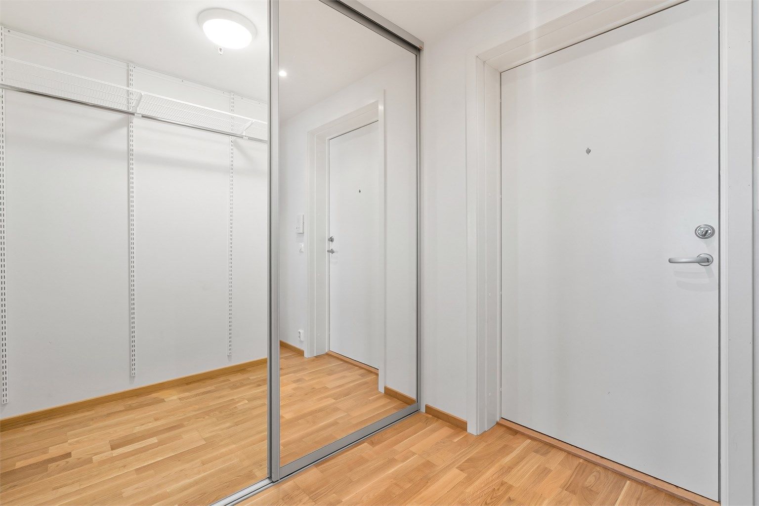 En stor skyvedørsgarderobe med speilfronter gir rikelig med oppbevaringsplass for yttertøy og sko.