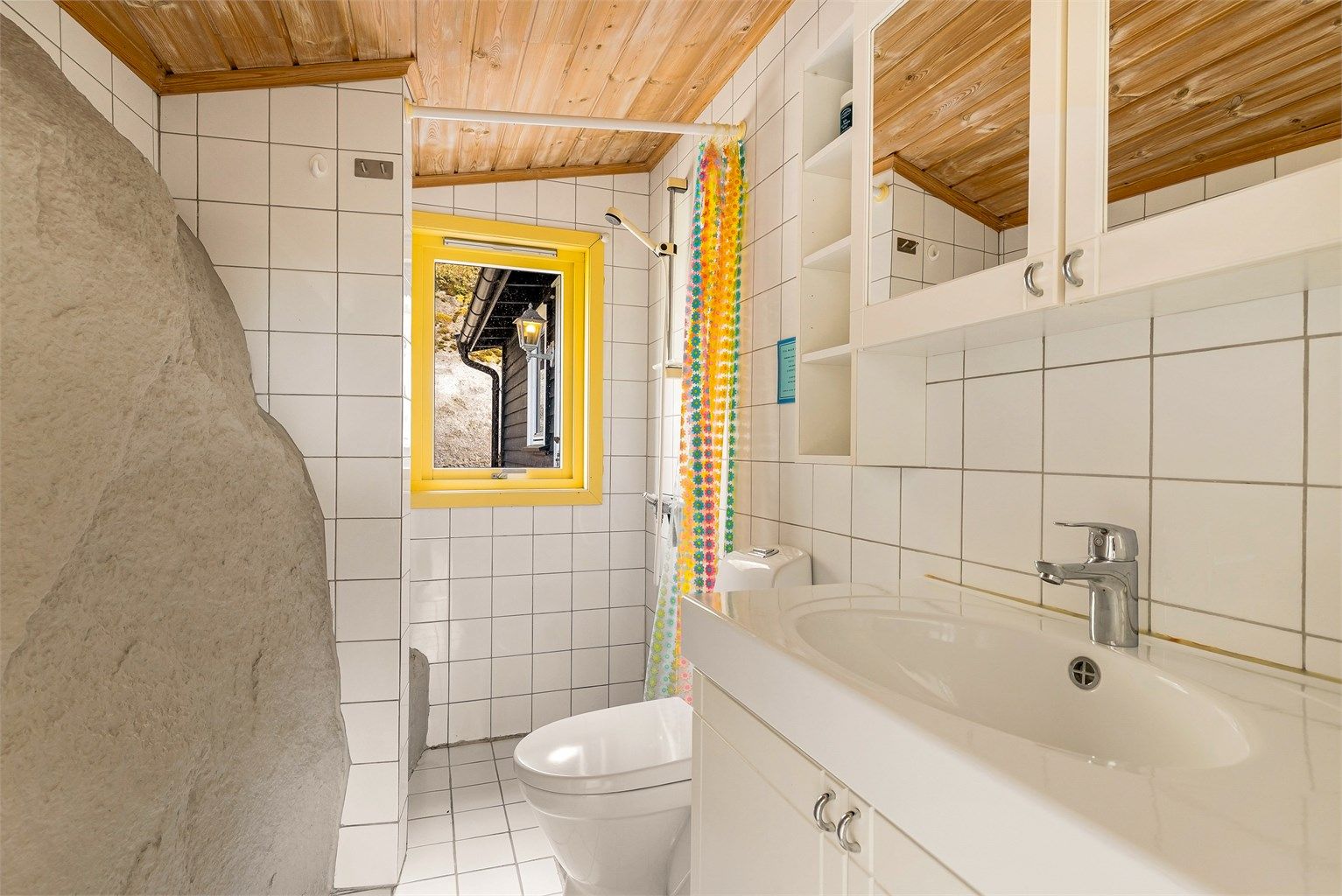 Badet har varmekabler i gulvet. En spesiell detalj er fjellet som er integrert i den ene veggen.
