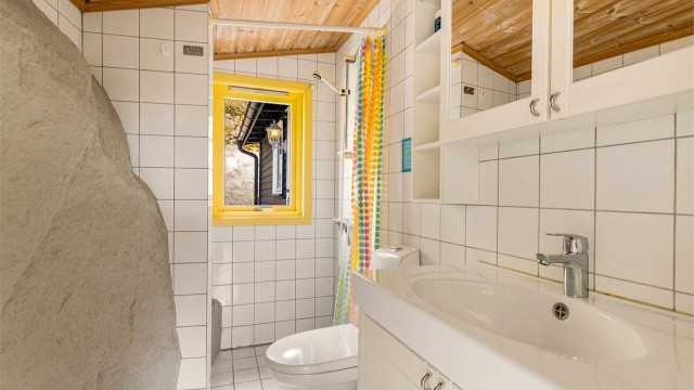 Badet har varmekabler i gulvet. En spesiell detalj er fjellet som er integrert i den ene veggen.