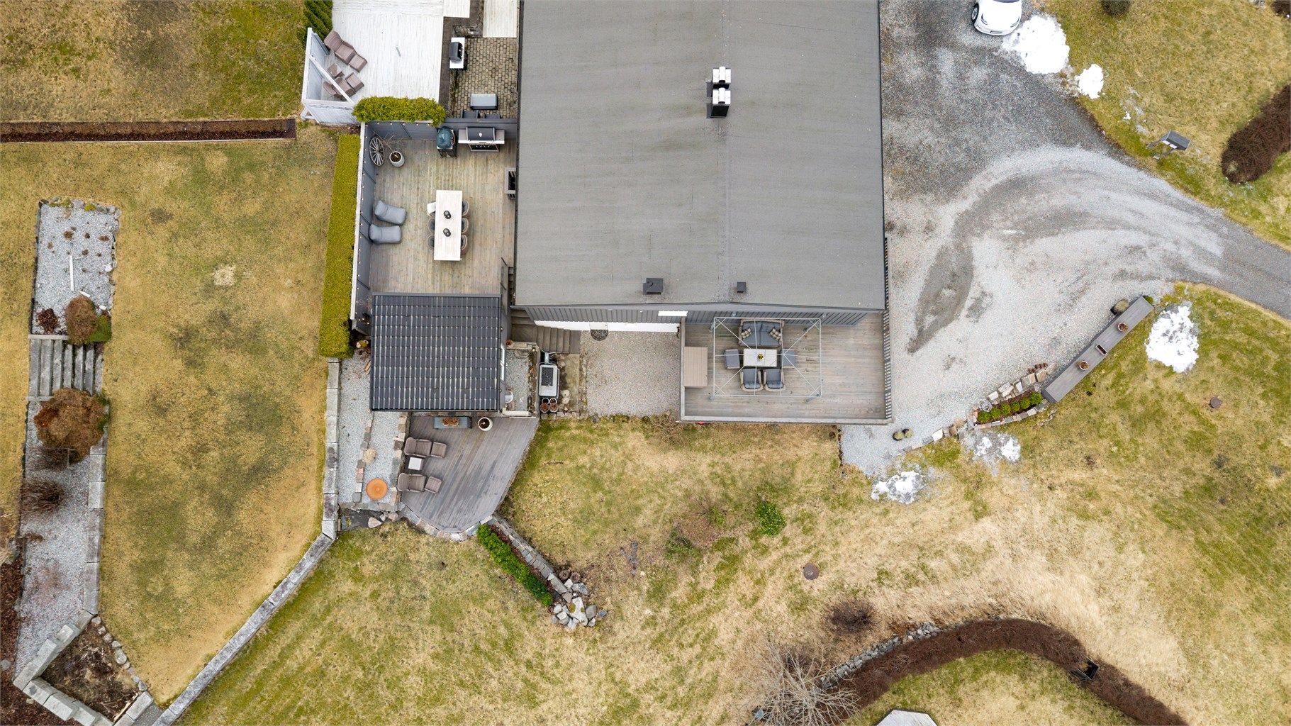 Tomten er opparbeidet med gruslagt gårdsplass, plenarealer og beplantning