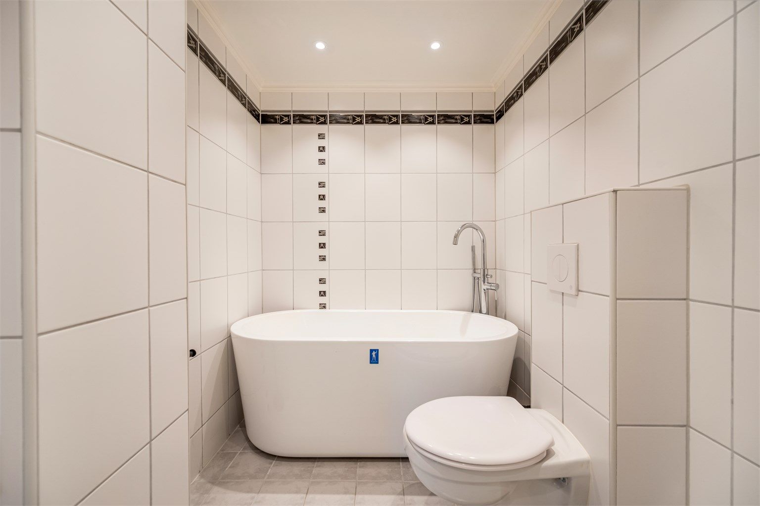 Det lyse, flislagte badet i første etasje byr på et frittstående badekar som inviterer til lange, avslappende bad, samt gulvvarme og vegghengt toalett.