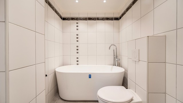Det lyse, flislagte badet i første etasje byr på et frittstående badekar som inviterer til lange, avslappende bad, samt gulvvarme og vegghengt toalett.