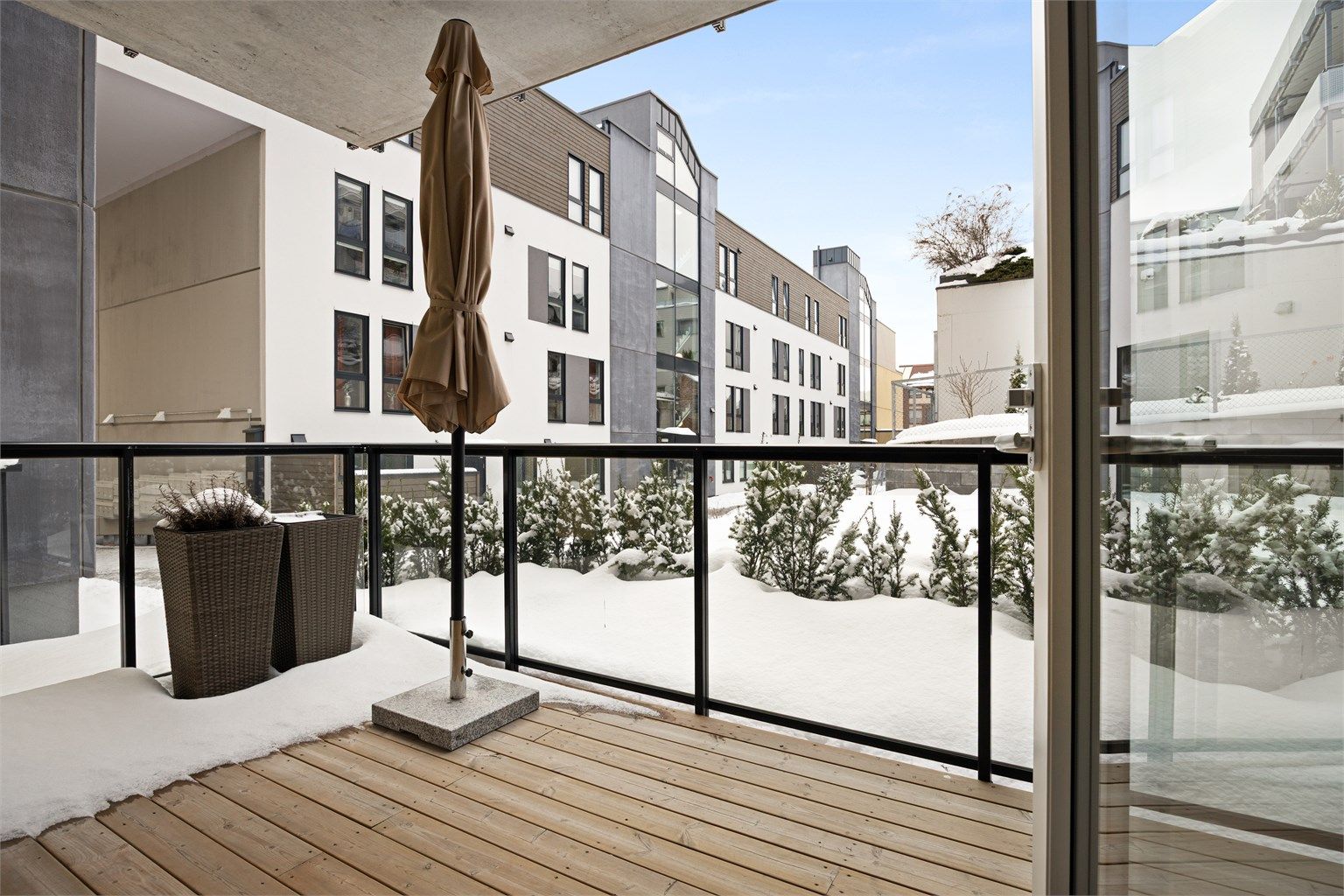 Terrasse med utvendig belysning, strømuttak, terrassebord på gulv og glassrekkverk.