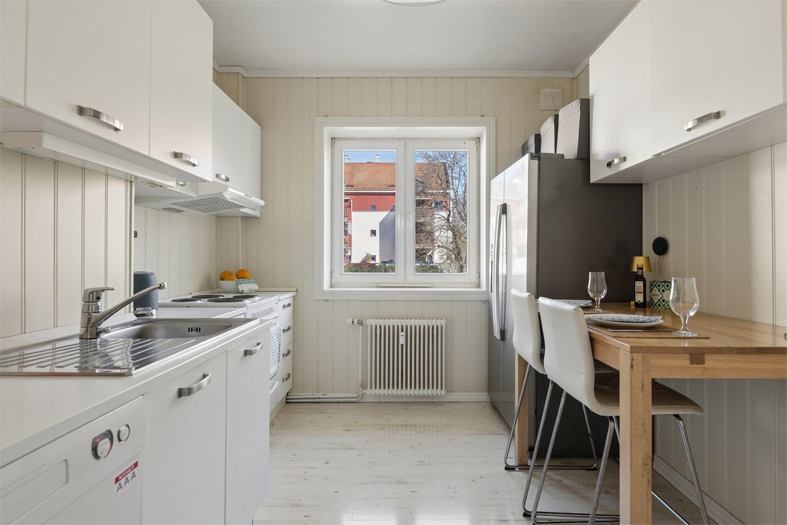 Kjøkkenet har innredning med glatte fronter og laminert benkeplate, samt frittstående hvitevarer.