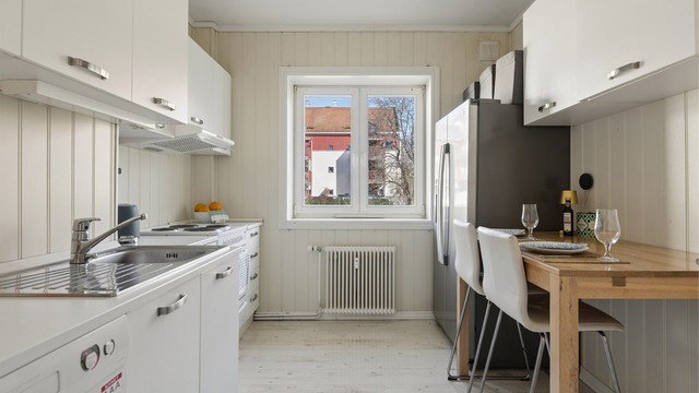 Kjøkkenet har innredning med glatte fronter og laminert benkeplate, samt frittstående hvitevarer.