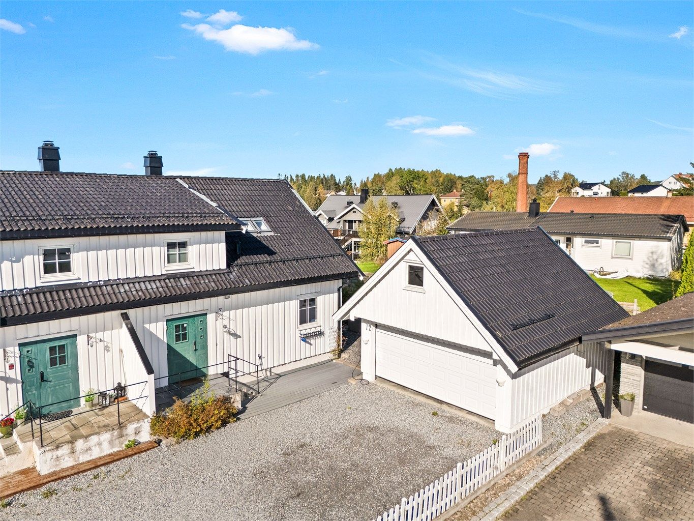 Inngangspartiet gir et solid førsteinntrykk med sin karakteristiske grønne inngangsdør, dekorert med innfelte glassfelt som både slipper inn lys og tilfører personlighet.