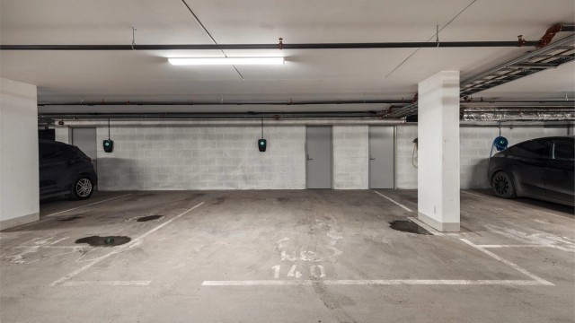 Stor parkeringsplass i lukket garasjeanlegg med lader for elbil montert.