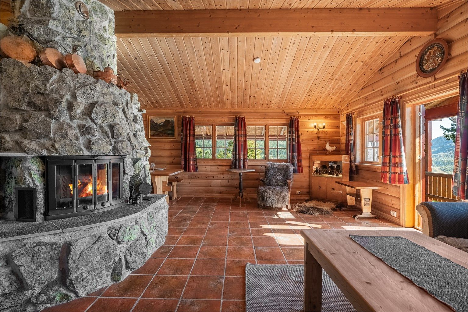 Stuen har god takhøyde under skråtaket, peisinnsats i naturstein og direkte utgang til overbygd terrasse.