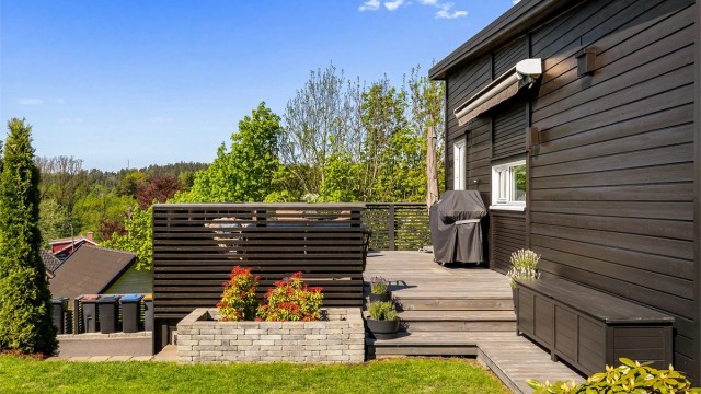 Uteplassen er pent rammet inn med beplantning og trapp ned til hagen ( samt trapp opp ved siden av garasjen )