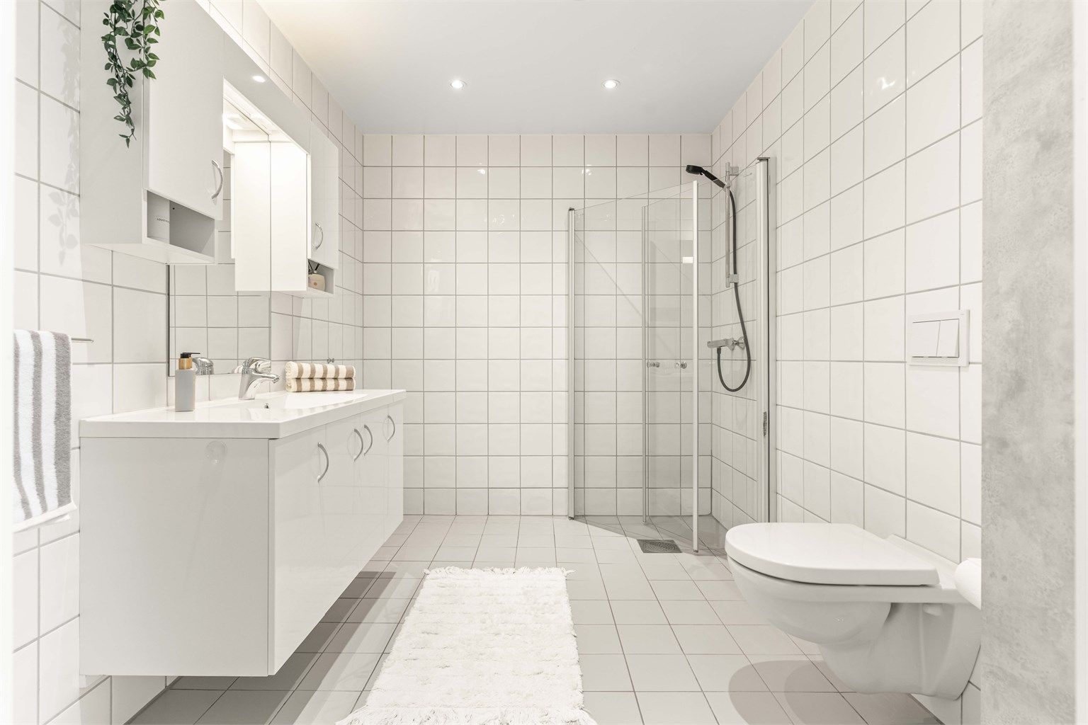 Badet i andre etasje har flislagte overflater, gulvvarme, vegghengt toalett og downlights i taket.