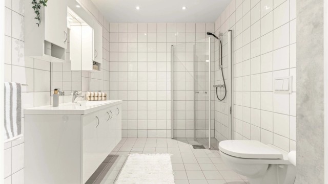 Badet i andre etasje har flislagte overflater, gulvvarme, vegghengt toalett og downlights i taket.