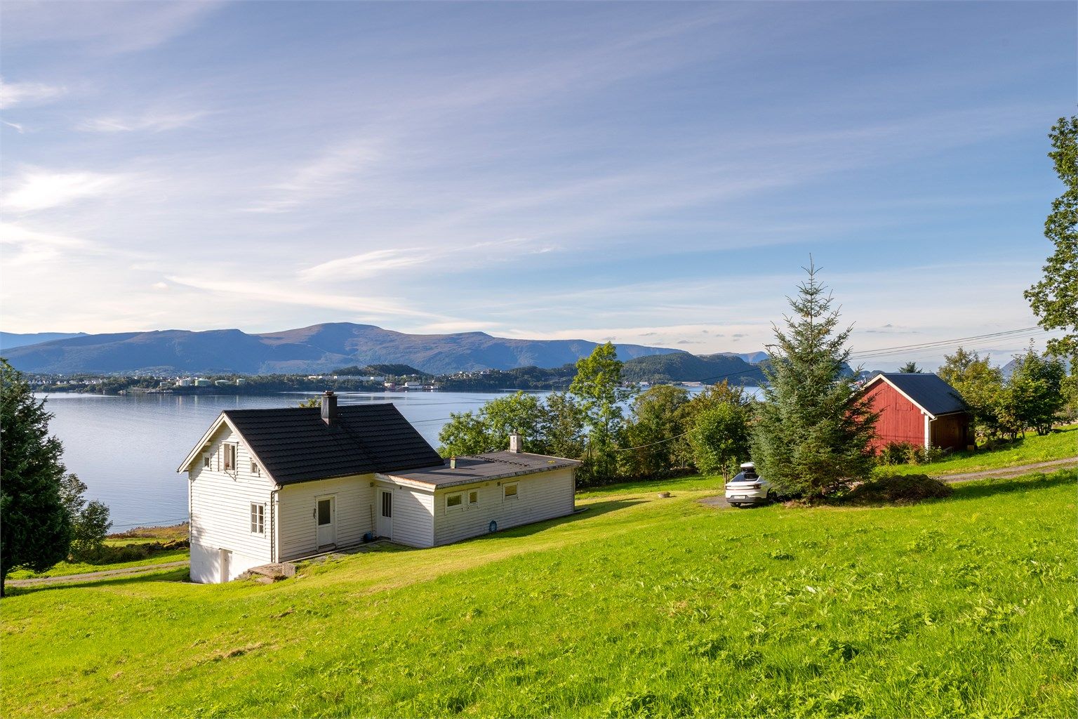 Eiendommen ligger i en sydvendt helling med enebolig, frittstående løe og åpen utsikt mot Ellingsøyfjorden.
Foto: [Fotograf eller fotofirma]