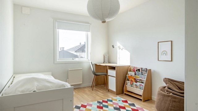 Et lyst og trivelig barnerom med parkett på gulvet.