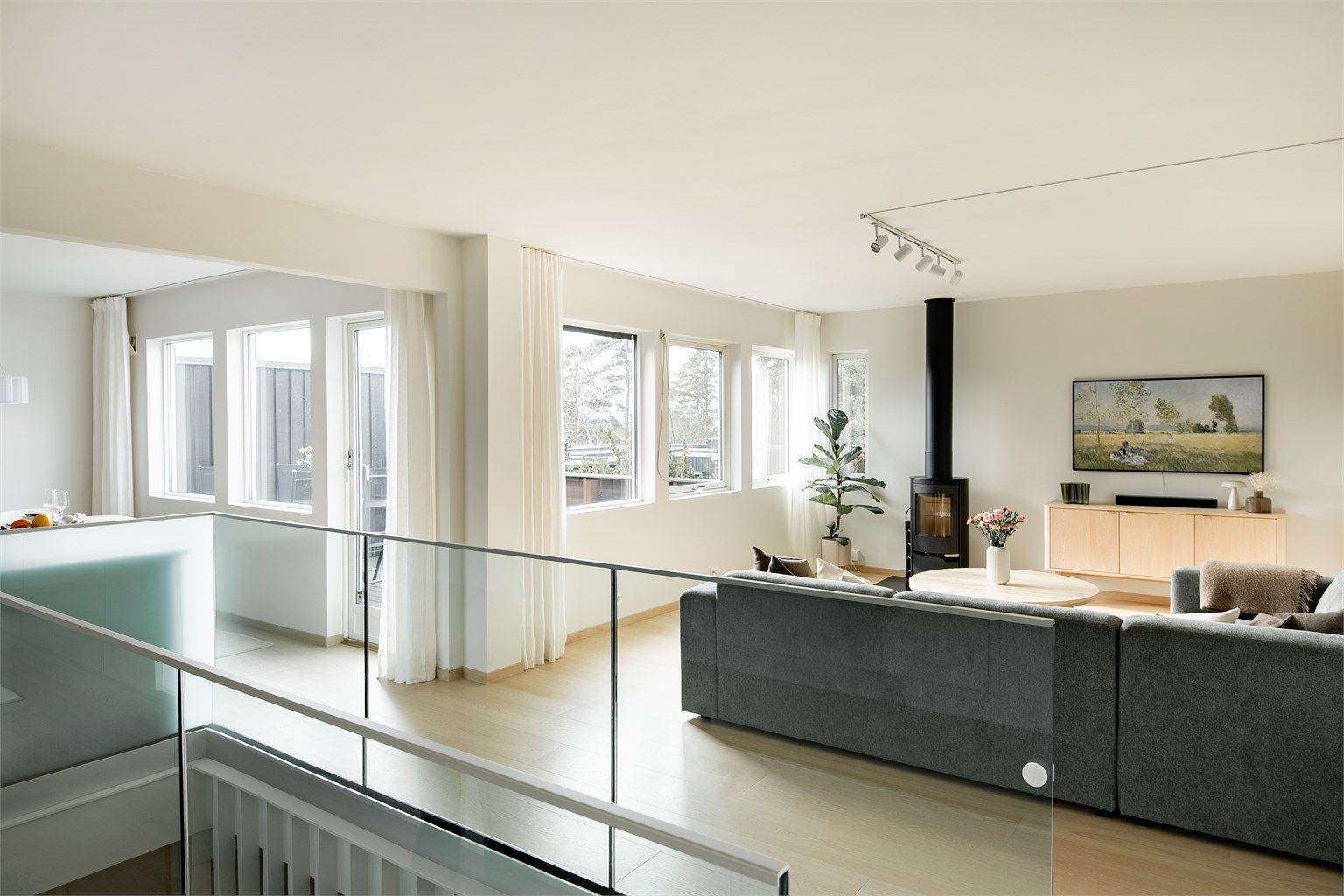 Fra trappen kommer du opp til et lyst og luftig allrom. Glassrekkverket sikrer en åpen romfølelse.