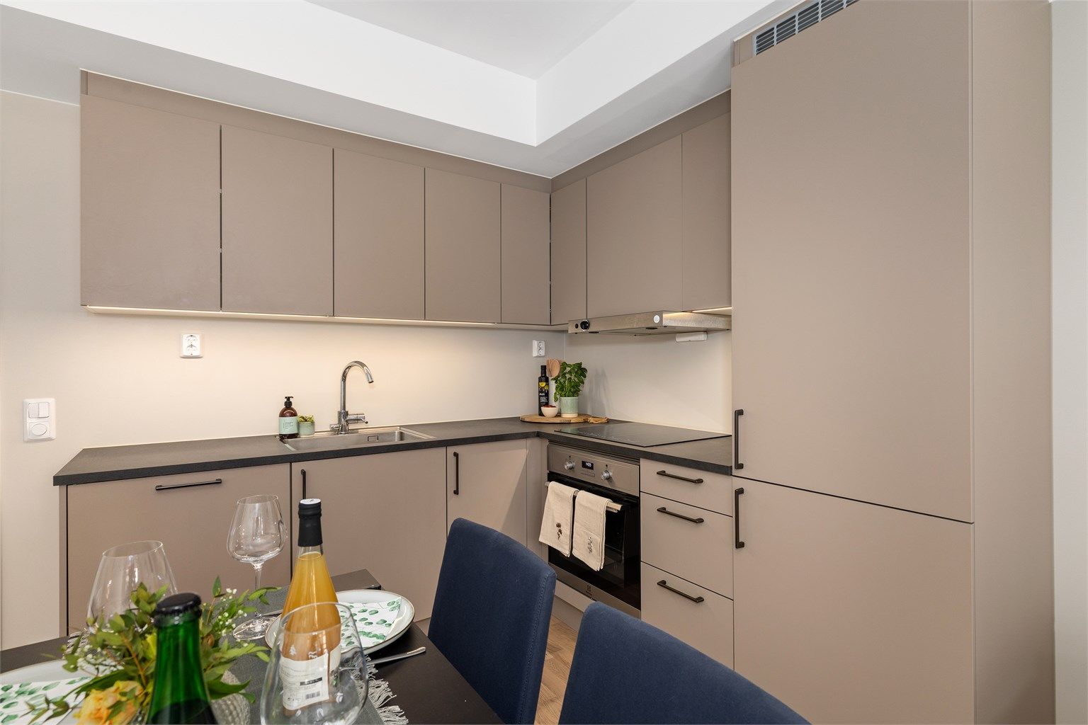 Kjøkkenet er innredet med integrerte hvitevarer og har gode lysforhold over arbeidsflatene.