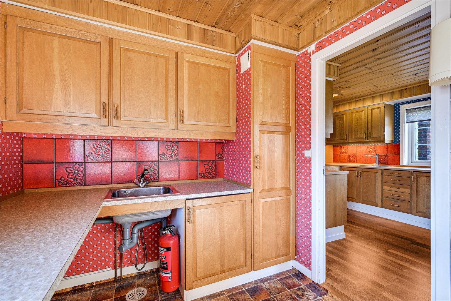 Praktisk vaskerom i tilknytning til kjøkkenet, med utslagsvask og opplegg for vaskemaskin.