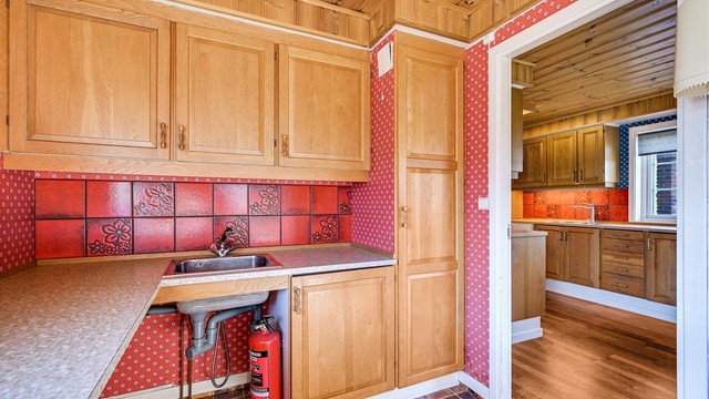 Praktisk vaskerom i tilknytning til kjøkkenet, med utslagsvask og opplegg for vaskemaskin.