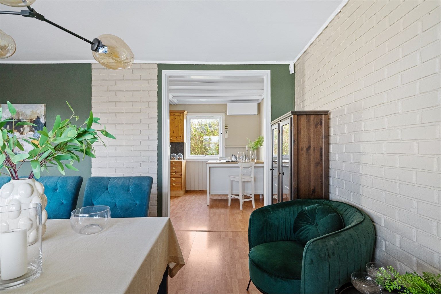 Kjøkken og spisestue i delvis åpen løsning. Vedovn plassert i rommet.  
