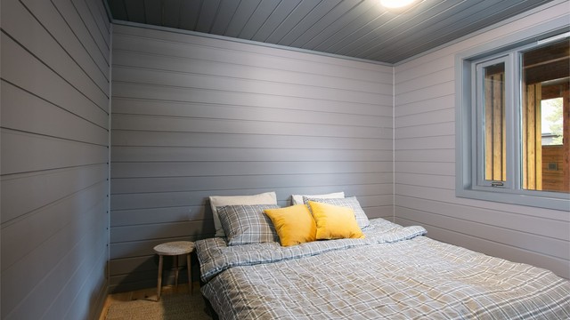 Soverom med malt trepanel på vegger og himling samt plass til dobbeltseng.