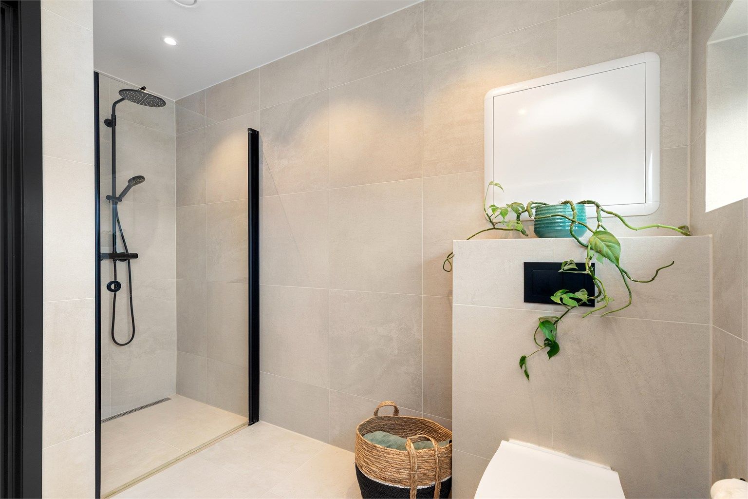 Romslig dusjnisje med dusjvegg i glass. Armatur med regnfallsdusj og hånddusj