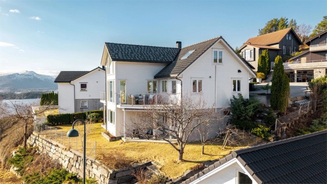 Eiendommen ligger høyt og fritt og har pent opparbeidet tomt med nautursteinsmurer, beplantning og plen