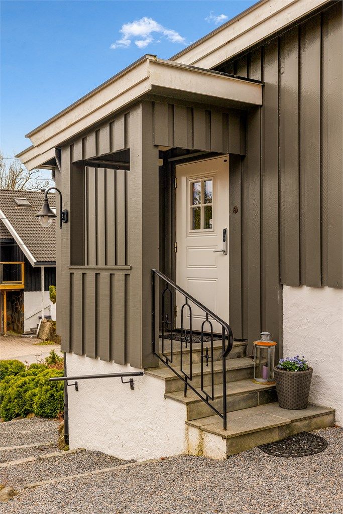 Det overbygde inngangspartiet har en profilert ytterdør i tre med kodelås.