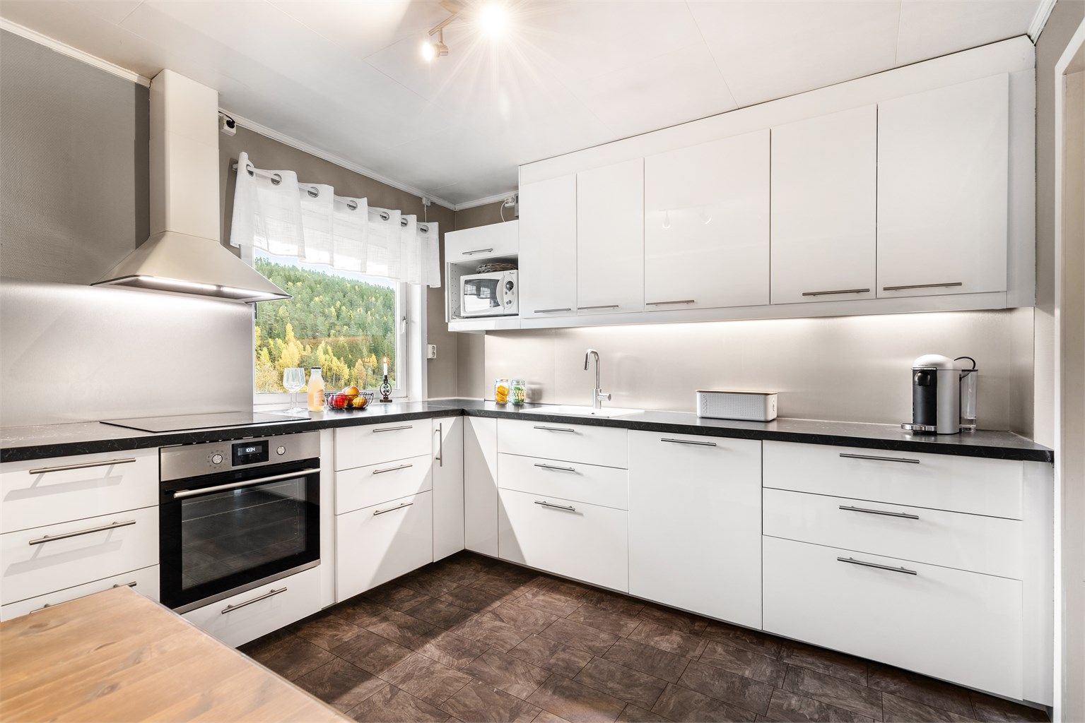 Separat kjøkken med IKEA innredning fra 2018, som har glatte fronter og benkeplate med laminert overflate. Det er nedfelt kjøkkenvask med armatur, samt benkeskapsbelysning og stikkontakter over kjøkkenbenk.