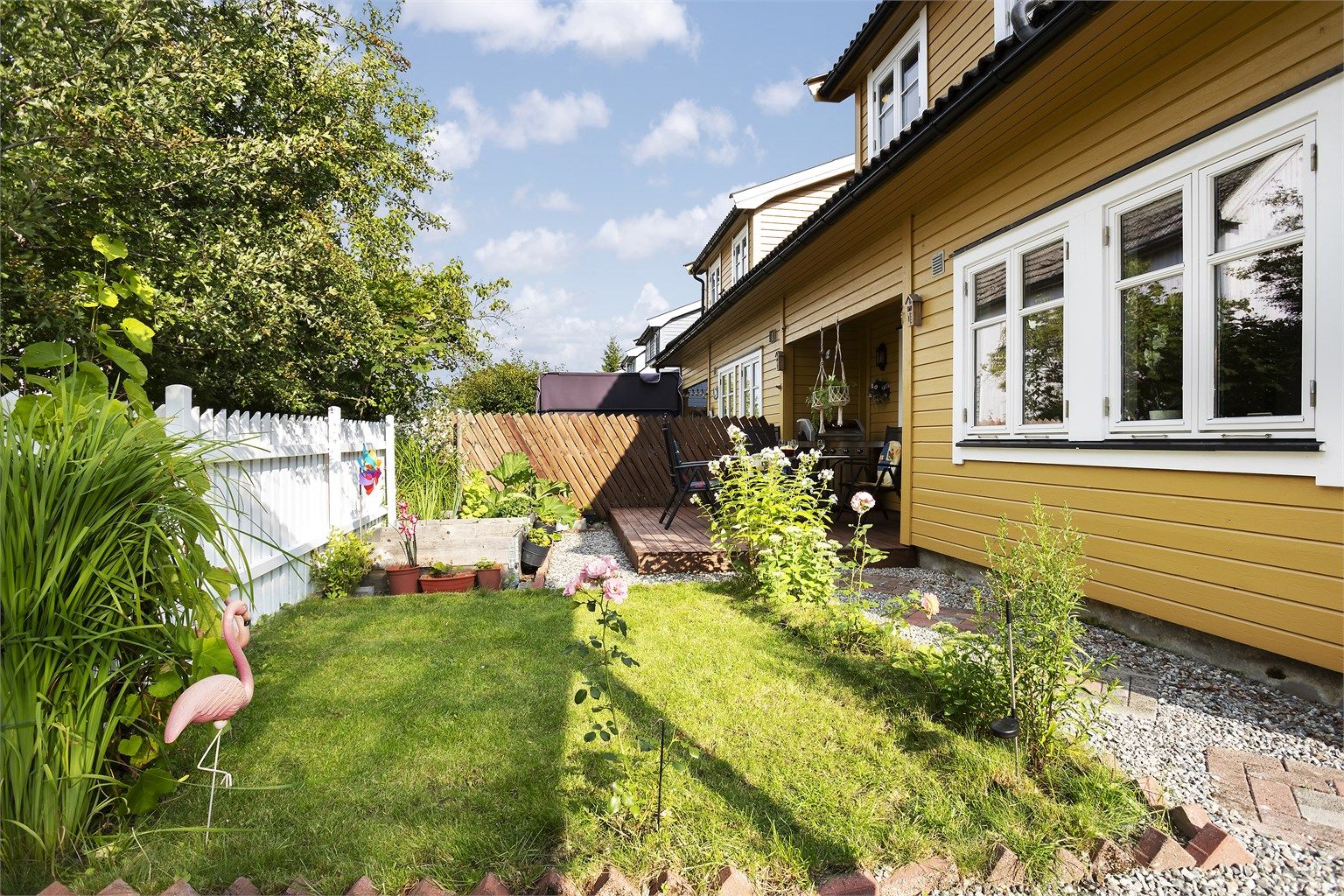 Hagen er pent opparbeidet med plen og beplantning.