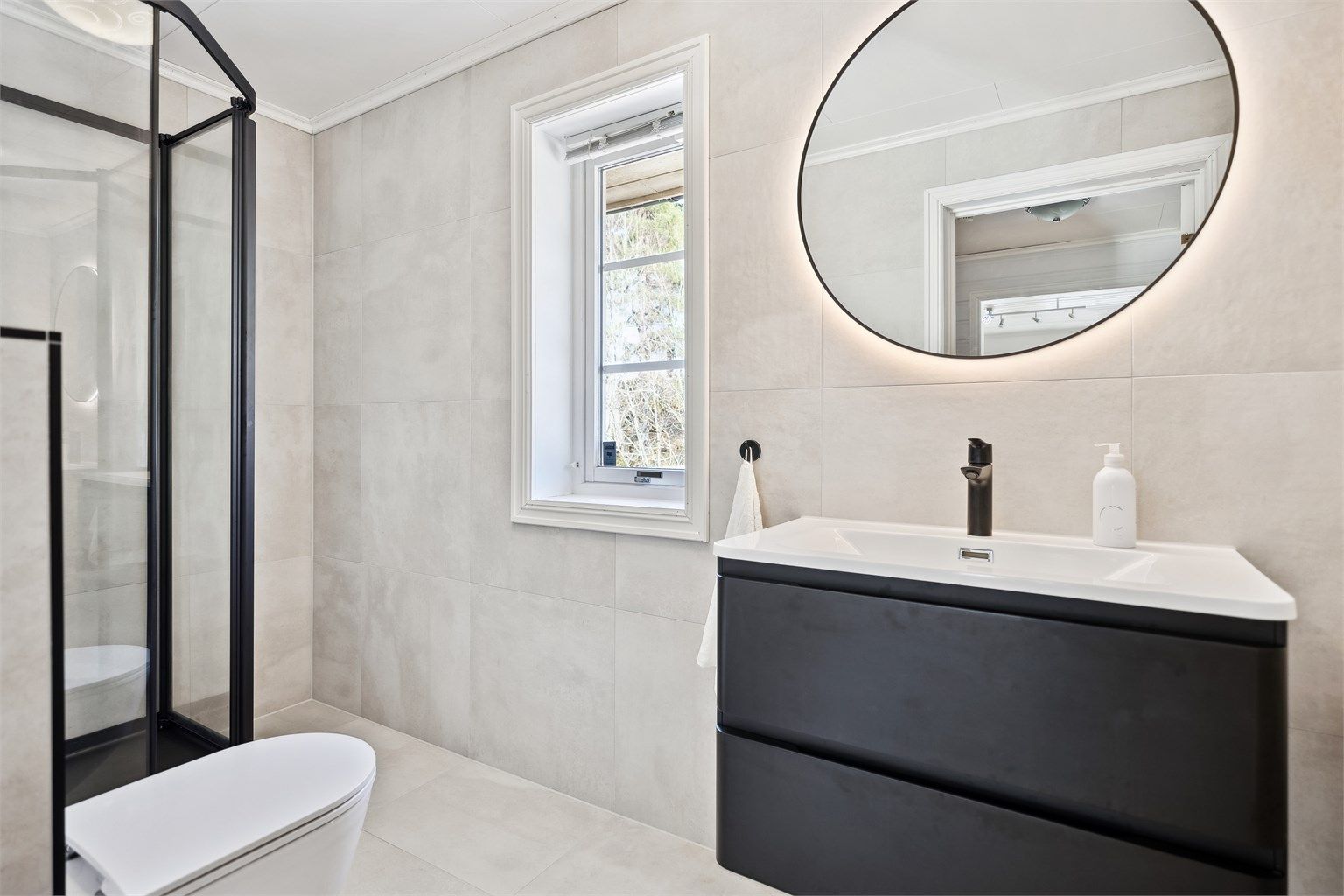 Lekkert oppusset bad med dusjkabinett, servantskap og vegghengt wc.