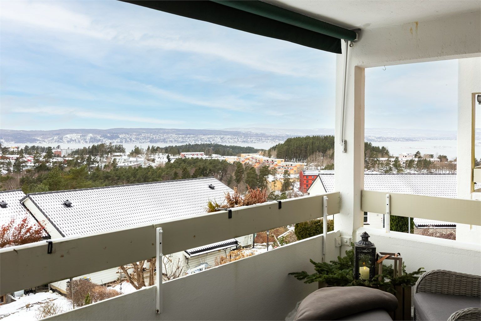 Balkongen har betonggulv belagt med plastheller, rekkverk i treverk og betong samt montert belysning og stikkontakter på vegg.