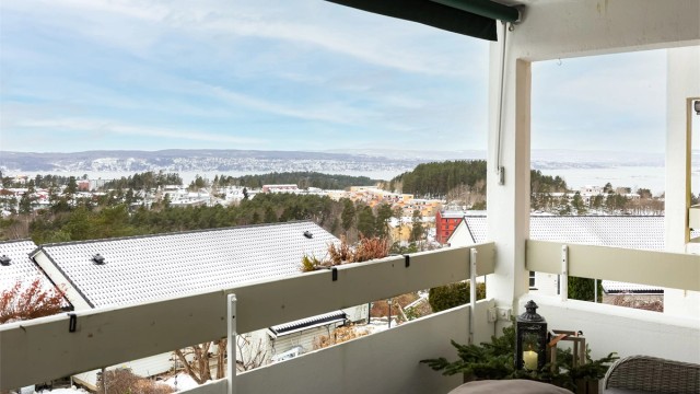 Balkongen har betonggulv belagt med plastheller, rekkverk i treverk og betong samt montert belysning og stikkontakter på vegg.