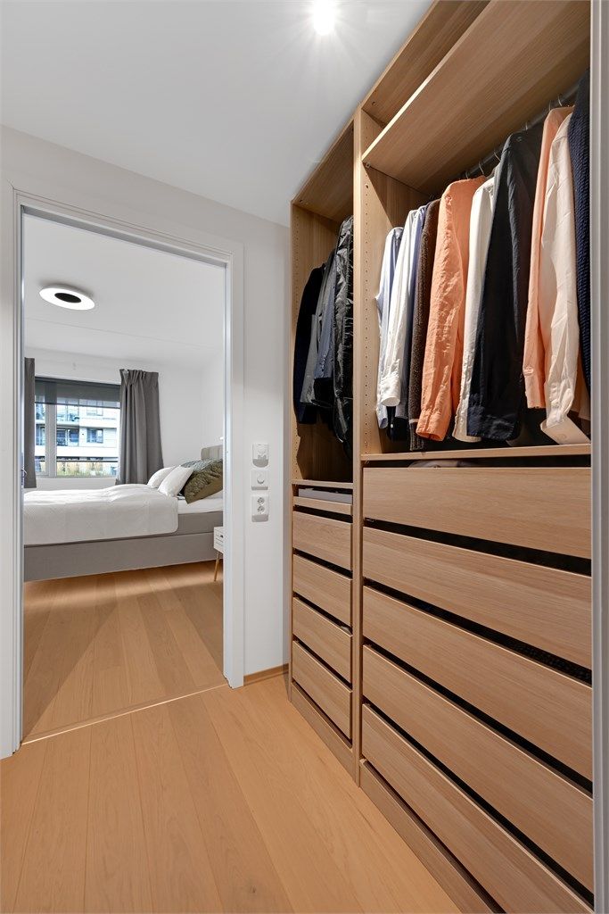 Innholdsrikt walk-in closet innredet med skuffer og oppheng, utstyrt med vannbåren gulvvarme.